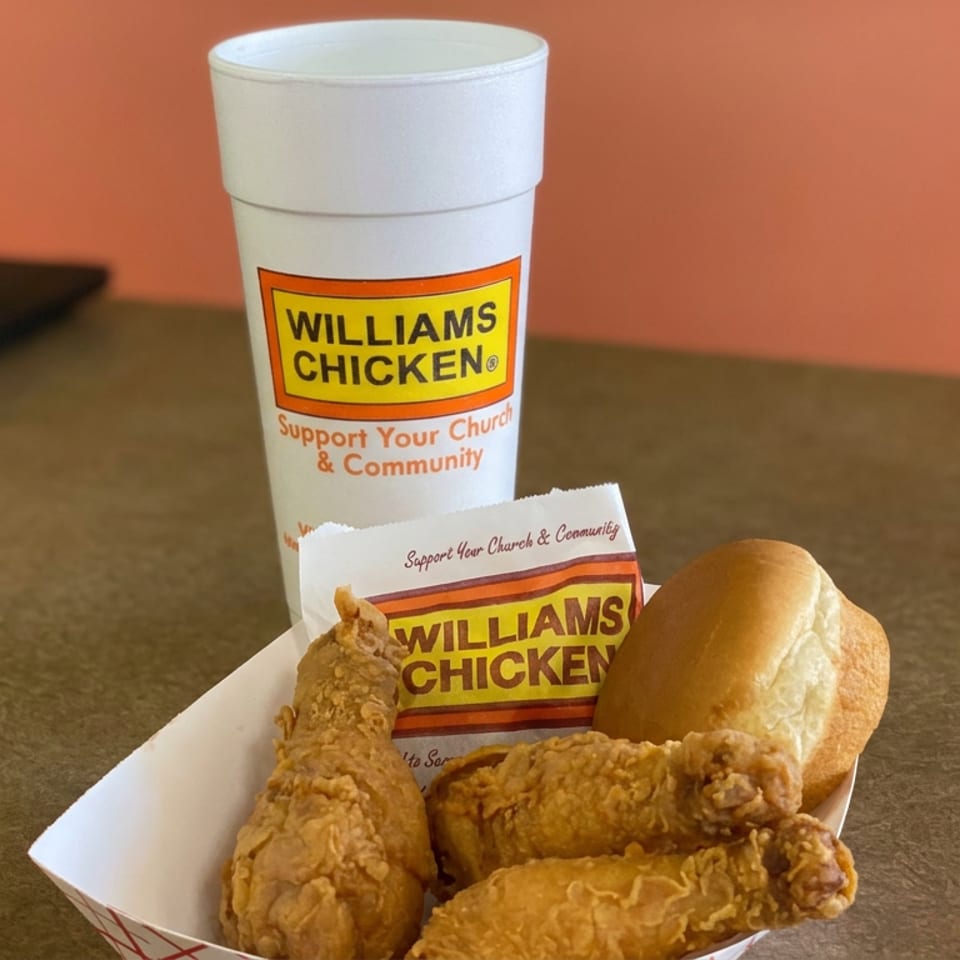 Williams Chicken meal featuring fried chicken pieces, a biscuit, branded wrapper, and drink cup on a table.