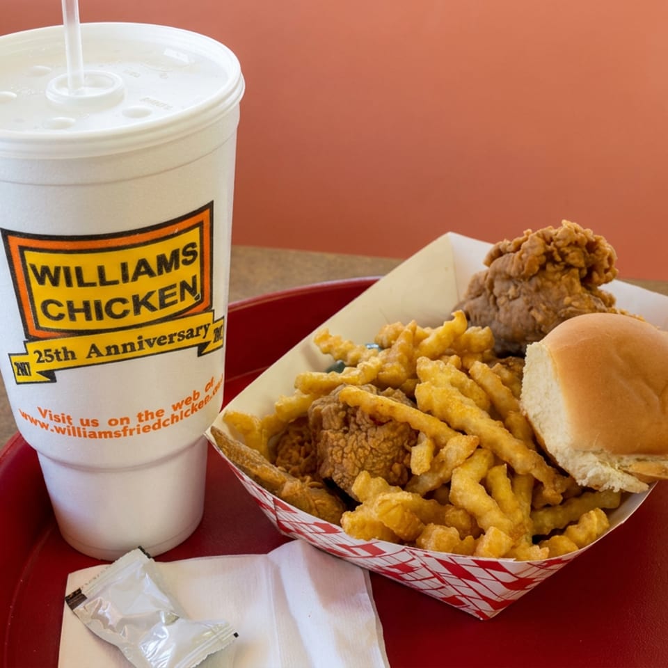 Williams Chicken meal with fried chicken, seasoned fries, a biscuit, and a large soft drink on a red tray.