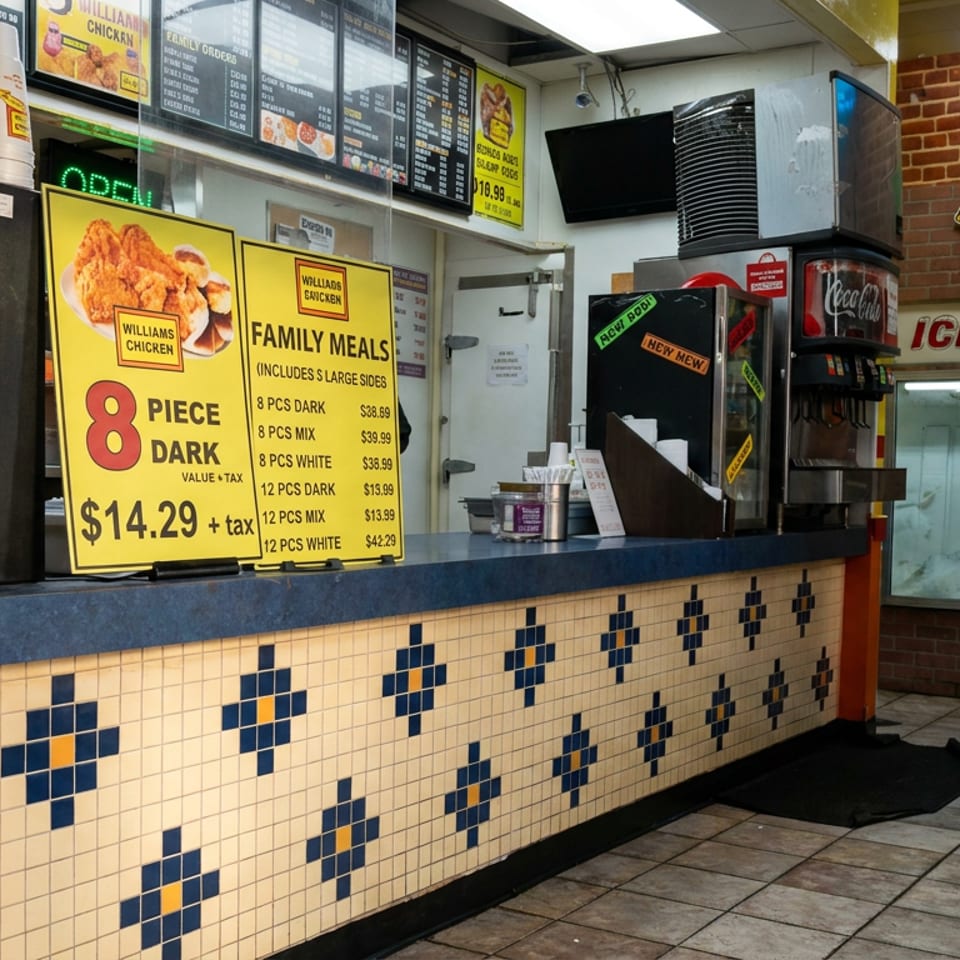 Williams Chicken restaurant counter displaying family meal menus, soda coolers, beverage fountain, and colorful tiled front.